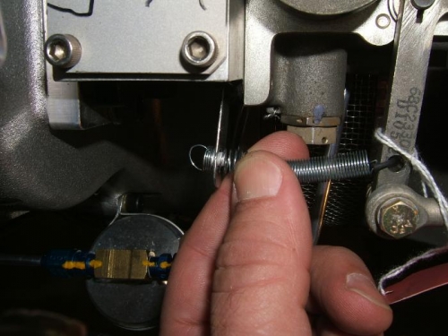 Throttle return spring secured over rivet