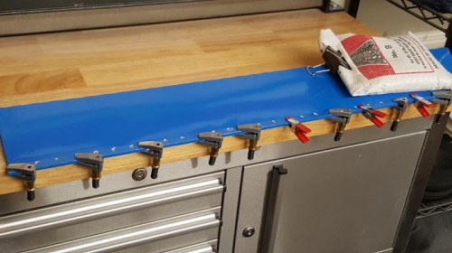 Elevator trim tab with glue curing while tab is held flat.