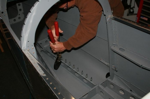 Squeezing the baggage floor nutplate rivets.