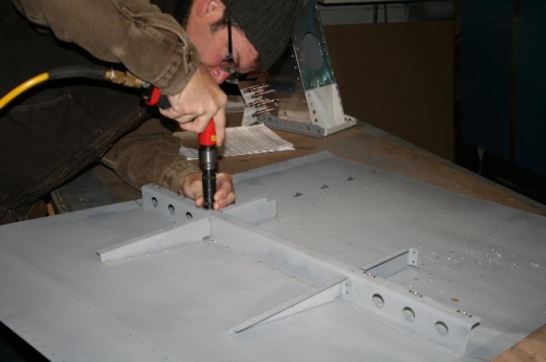Machine countersinking forward floor panel nutplate holes.