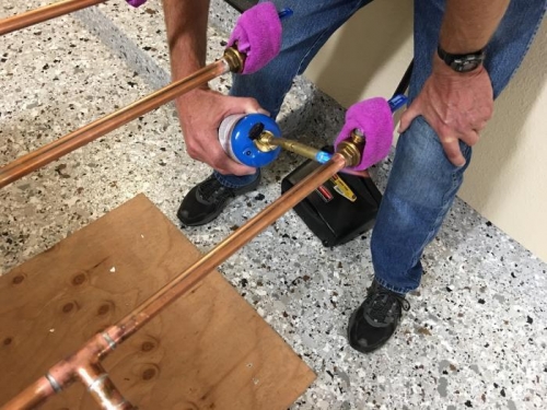 Heating a ball valve prior to soldering. The moist rag helps protect the ball valve seals from heat.