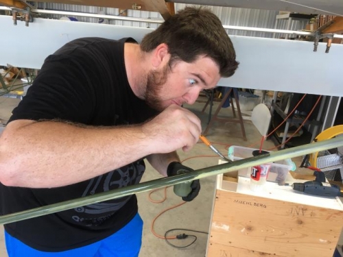 Derrick applies epoxy paint to the left wing strut.