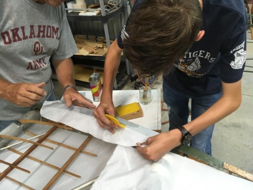 Lawson attaches the fabric to the right wingtip while Eric guides the work
