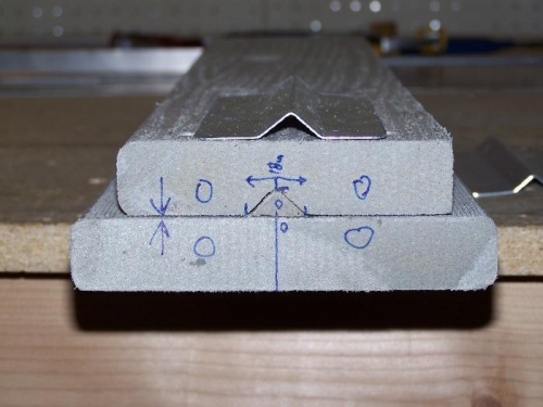 Side view of press die with completed sample hat stiffener on top to show profile of completed part.