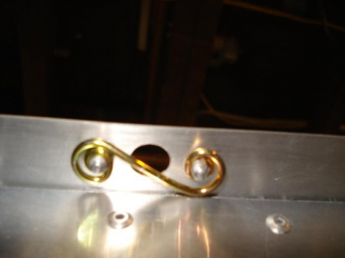 The spring riveted in place looking from the bottom side of the locker door stop.