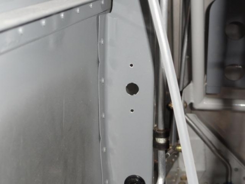 The holes drilled in the left bulkhead for the oil cooler shutter cable