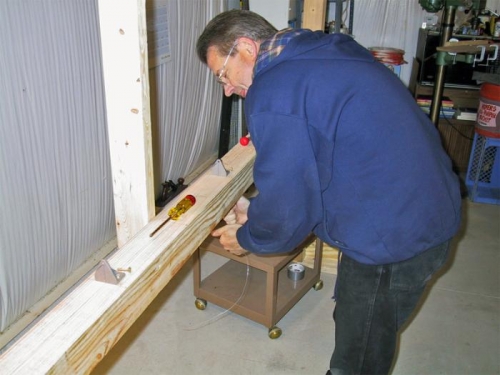 Les fastens the fixture brackets to the horizontal crosspiece.