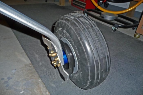 Closeup of wheel, tire, wheel pant mounting bracket, and gear leg.