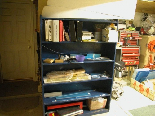The shelves in front of the work table with wing parts.