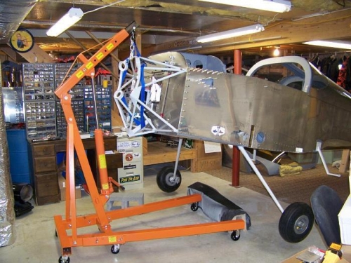 Shop hoist lifting plane by engine mount, main gear installed