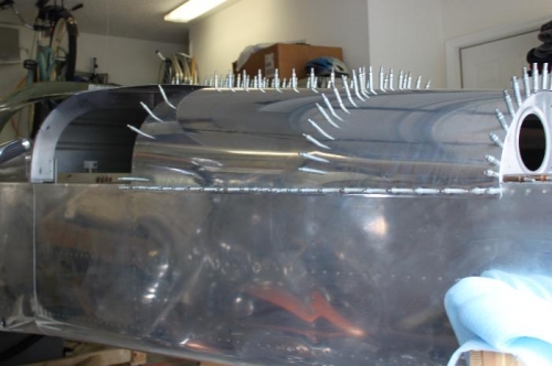 Reinstalling the aft top skins after rolling the overlap edges and dimpling.