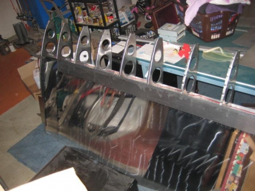 A stack of wing skins against a framed wing.