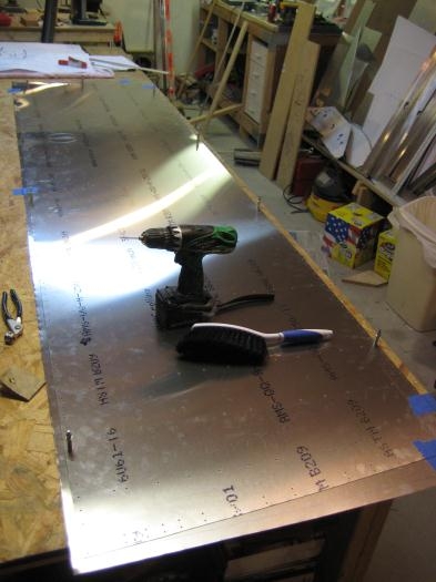 Completed skin to act as pattern, on top of rough cut aluminum sheet for second skin. Note clecos.