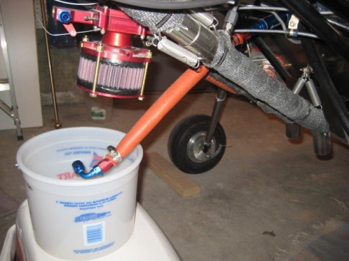 Fuel line removed from carburetor, to fill graduated bucket.