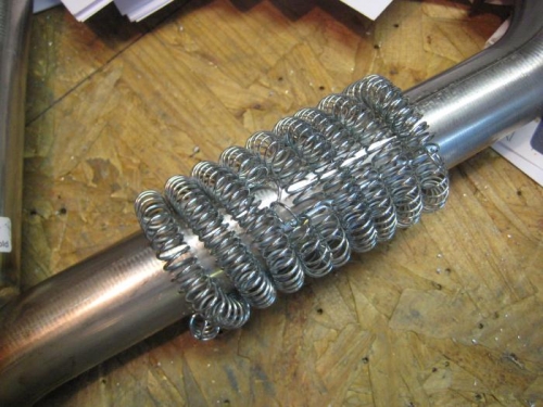 Screen door spring, expanded and wrapped around the exhaust pipe.