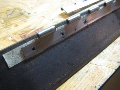 Closeup of the double-sided carpet tape holding the piano hinge, + lots of holes