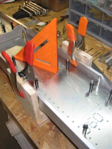 Spacing jigs with clamps holding spar caps against them, to maintain spacing.