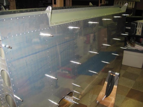 Outboard right wing bottom skin on the skeleton for deburring operation.